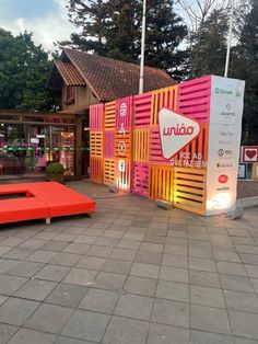 an orange couch sitting on top of a sidewalk next to a pink and yellow building