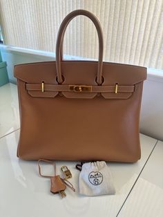 This Hermes Birkin 35 bag is a vintage piece with a natural courchevel exterior made of leather. The bag features a large size and gold hardware accents. The lining is also made of leather with a gold lining color. The bag has a top handle and is designed for women. The brand is Hermes and the model is Birkin 35. This is in the Natural color, which is just a Vintage Birkin, Vintage Hermes Bag, Hermes Vintage, Hermes Birkin 35, Vintage Hermes, Hermes Bag, Hermes Birkin, Designer Bags, Natural Color