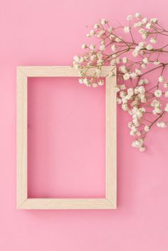 a white frame sitting on top of a pink wall next to a small branch of baby's breath