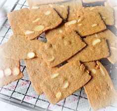 a bunch of cookies that are sitting on a wire rack with some almonds in the middle