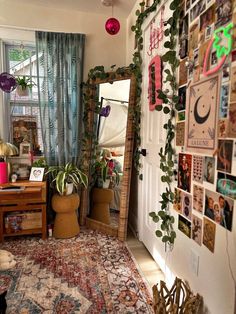 a living room filled with lots of plants and pictures on the wall next to a door