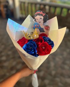 a hand holding a bouquet with red, white and blue flowers in it while wearing a tiara