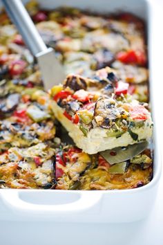 a white casserole dish filled with vegetables and cheese