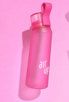 a pink water bottle with the word air up on it sitting against a pink background