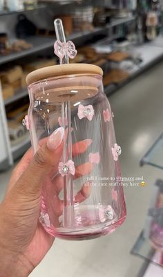 a person holding up a glass jar with pink flowers on it