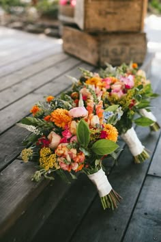 wedding bouquets are lined up on a wooden bench outside in front of an old box