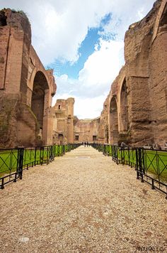 the walkway is lined with stone pillars and arches, leading to an ancient building that looks like it has been built on land