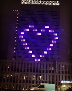 a large building with purple lights on it's side in the city at night