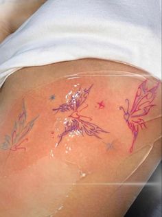 the back of a woman's thigh with tattoos on it and flowers painted on her thighs