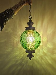 a green glass light hanging from a ceiling fixture in a room with yellow and white lighting