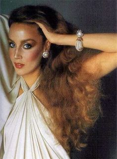 a woman with long brown hair and blue eyes wearing a white dress is posing for the camera