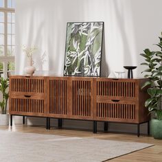 a living room with a large wooden cabinet and potted plants on the sideboard