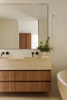 a bathroom with two sinks and a large mirror above it's counter top, along with a bathtub in the foreground