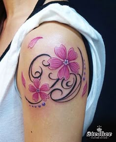 a woman's arm with pink flowers on it and the letter g in the middle