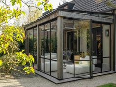 a room with glass walls and couches in the middle of an outdoor patio area