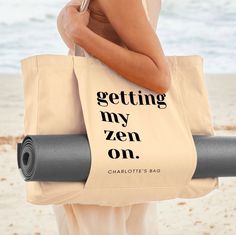 a woman carrying a yoga mat and tote bag with the words getting my zen on