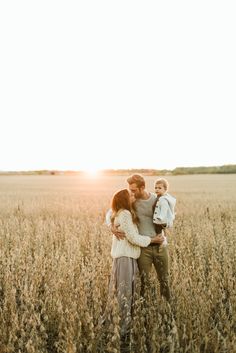 a woman and her son are standing in the middle of a wheat field at sunset