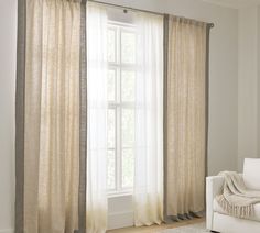 a white couch sitting next to a window in a living room under a large curtain