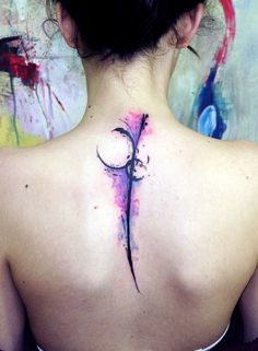 the back of a woman's neck with a tattoo design on her lower back