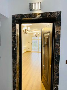 an open door leading into a room with wood floors and white walls on either side