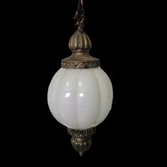 a white glass light hanging from a metal fixture on a black background with clippings