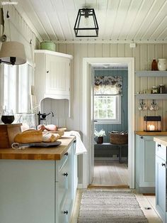 a narrow kitchen with white cabinets and wood flooring, along with an open door leading to the dining room