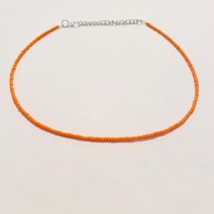 This beautiful necklace is handmade with dainty orange seed beads. It comes in a variety of lengths (14, 16, 18, 20, 22, or 24 inches) ranging from a choker fit to a longer necklace. Each necklace also comes with additional extender chain, making the necklace easily adjustable! The orange color is perfect for fall and Halloween and goes well with so many different outfits! Orange Beaded Choker With Round Beads, Adjustable Orange Beaded Necklace, Orange Choker With Colorful Beads, Adjustable Orange Choker With Round Beads, Adjustable Orange Single Strand Beaded Necklace, Orange Beaded Choker Jewelry, Adjustable Orange Beaded Necklaces With Tiny Beads, Adjustable Orange Beaded Necklace With Tiny Beads, Orange Single Strand Beads For Gift