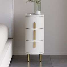 a white cabinet with three drawers and flowers in the vase on it's side