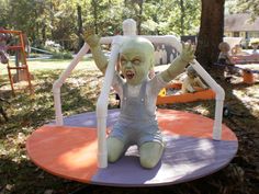 a creepy doll sitting on top of a purple and orange play ground in the park