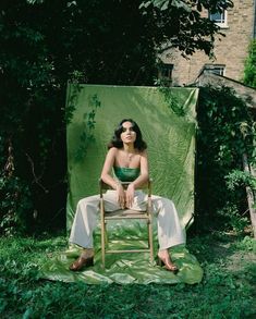 a woman sitting on a chair in front of a green screen with her eyes closed