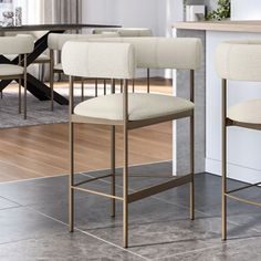 two white bar stools sitting next to each other in front of a kitchen counter