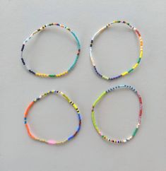 four bracelets made out of beads on a white surface with one bead in the middle