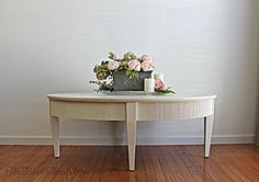 a white table with flowers on top and candles in the middle, against a wall