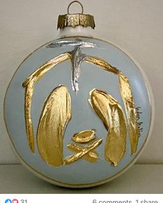 a glass ornament with gold leaf designs on the front and side of it