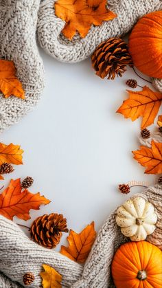 knitted sweaters, pumpkins and pine cones are arranged in a circle on a white background