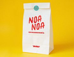 a paper bag with the words noa noa on it sitting against a yellow background