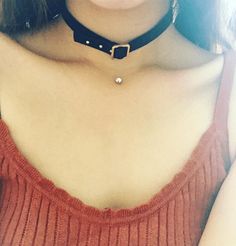 a close up of a person wearing a choker and holding a cell phone in their hand