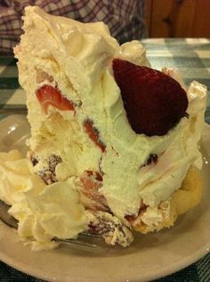 a piece of cake on a plate with a fork in it and a strawberry on top