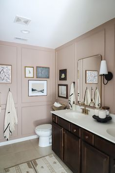 a bathroom with pink walls and pictures on the wall