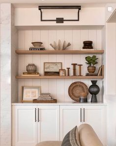 a living room filled with lots of furniture and shelves covered in books, vases and other items