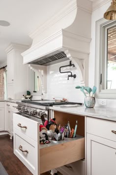 an open drawer in the middle of a kitchen with many utensils on it