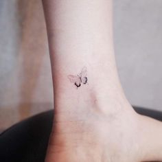 a small tattoo on the ankle of a woman's foot, with a butterfly