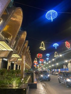 cars are driving down the street with christmas lights hanging from the wires above them and in front of buildings