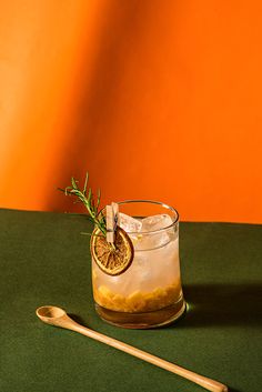 a glass filled with lemonade sitting on top of a table next to a spoon