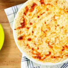 a cheese pizza sitting on top of a white plate next to a yellow bowl and fork