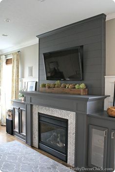 a dog is sitting in front of a fireplace with a flat screen tv above it