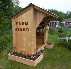 a small wooden stand with flowers in it and the words farm stand written on it