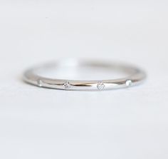 a white gold ring with three diamonds on the side, sitting on a plain surface