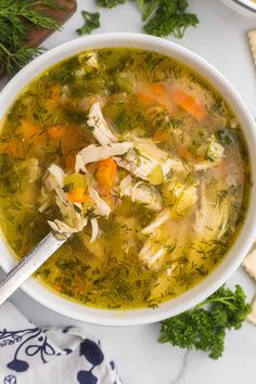 a white bowl filled with chicken and vegetable soup on top of a table next to crackers