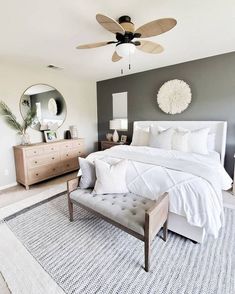 a bedroom with a bed, dresser and ceiling fan in the middle of the room